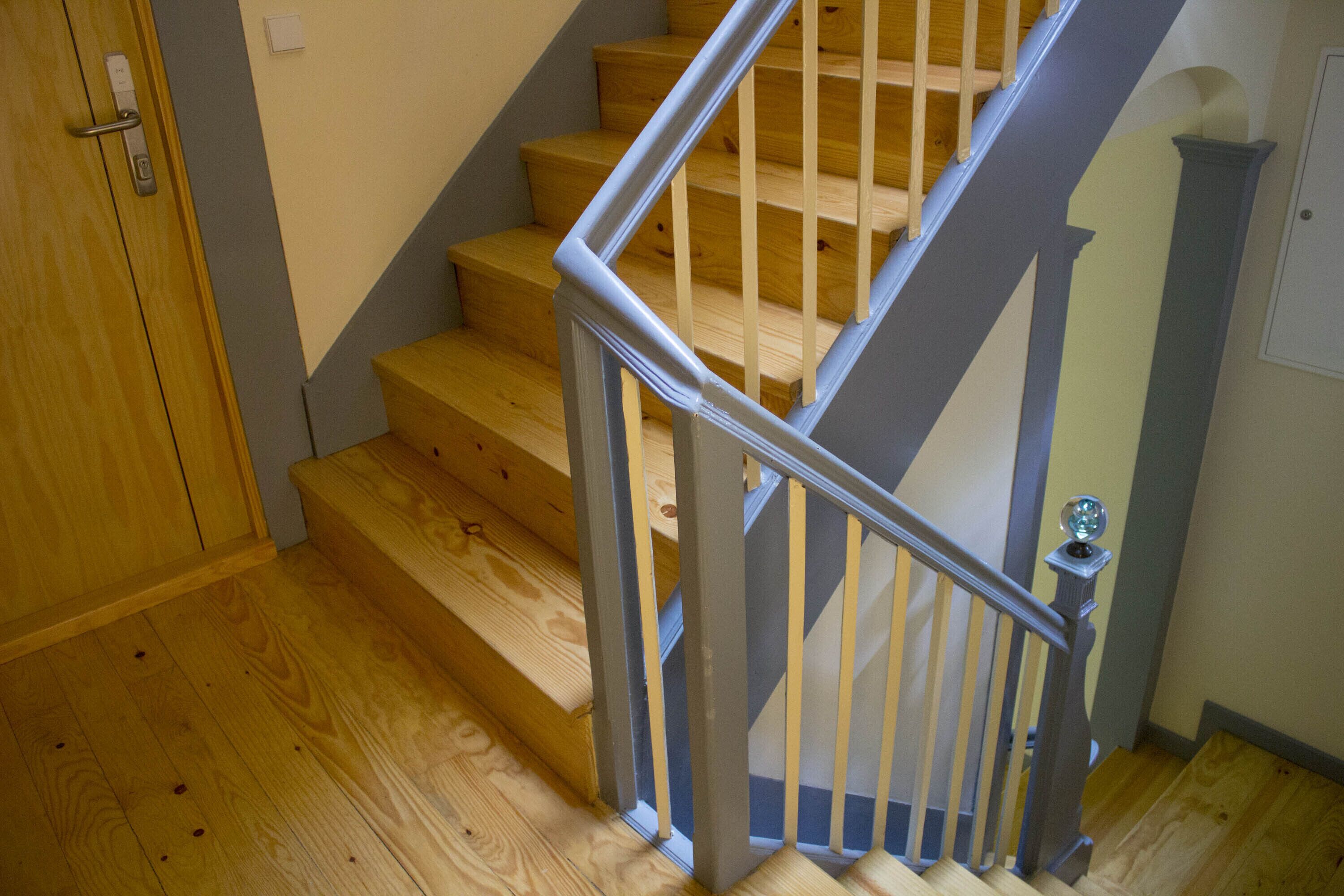 A wooden staircase with a metal handrail and a door with a handle.