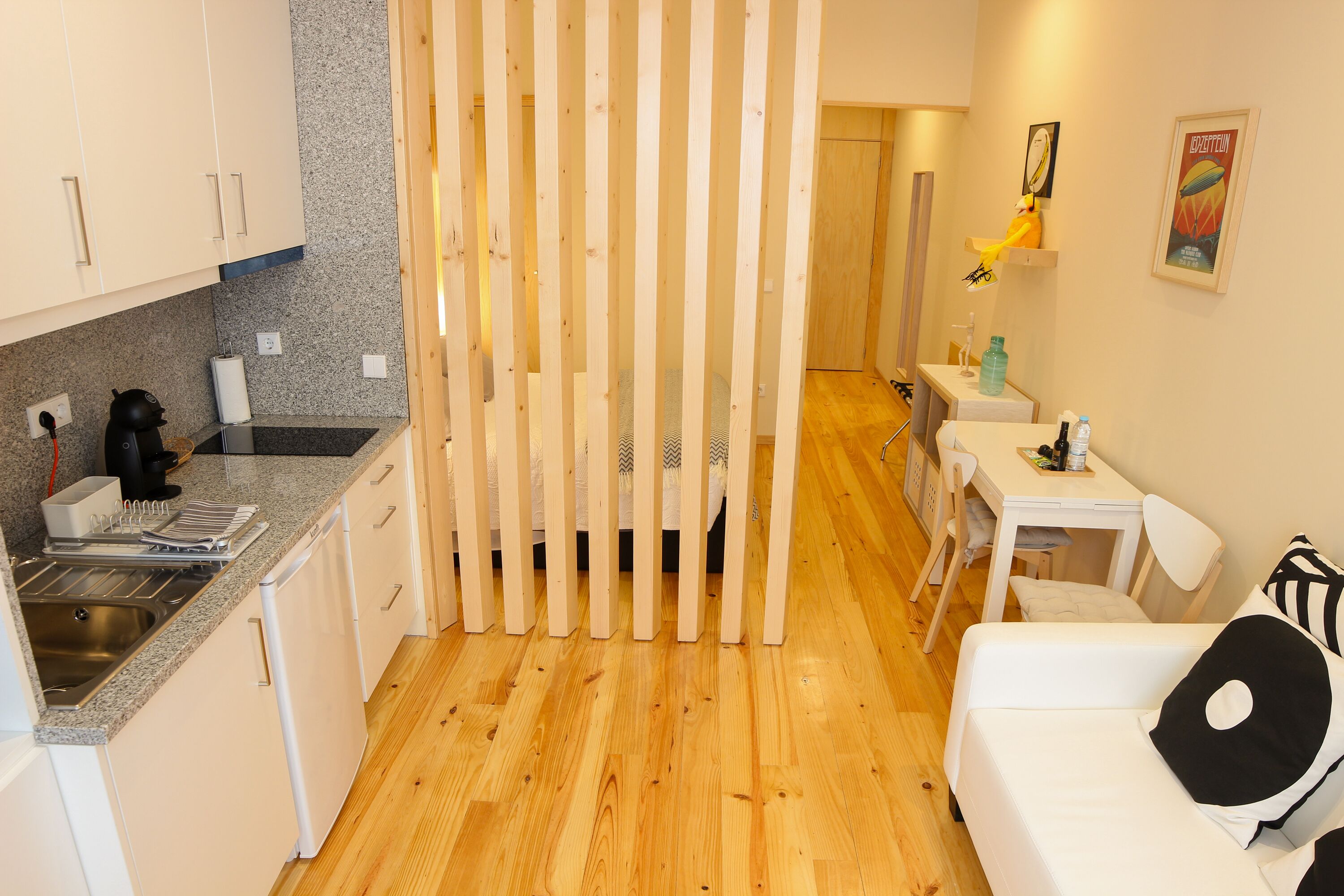 Habitación de hotel compacta con kitchenette, zona de comedor y cama con almohada blanco y negro.