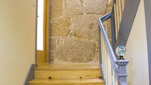 A wooden staircase with a stone wall background and a metal railing with a decorative finial. - Cedofeita Back Garden (Porto)