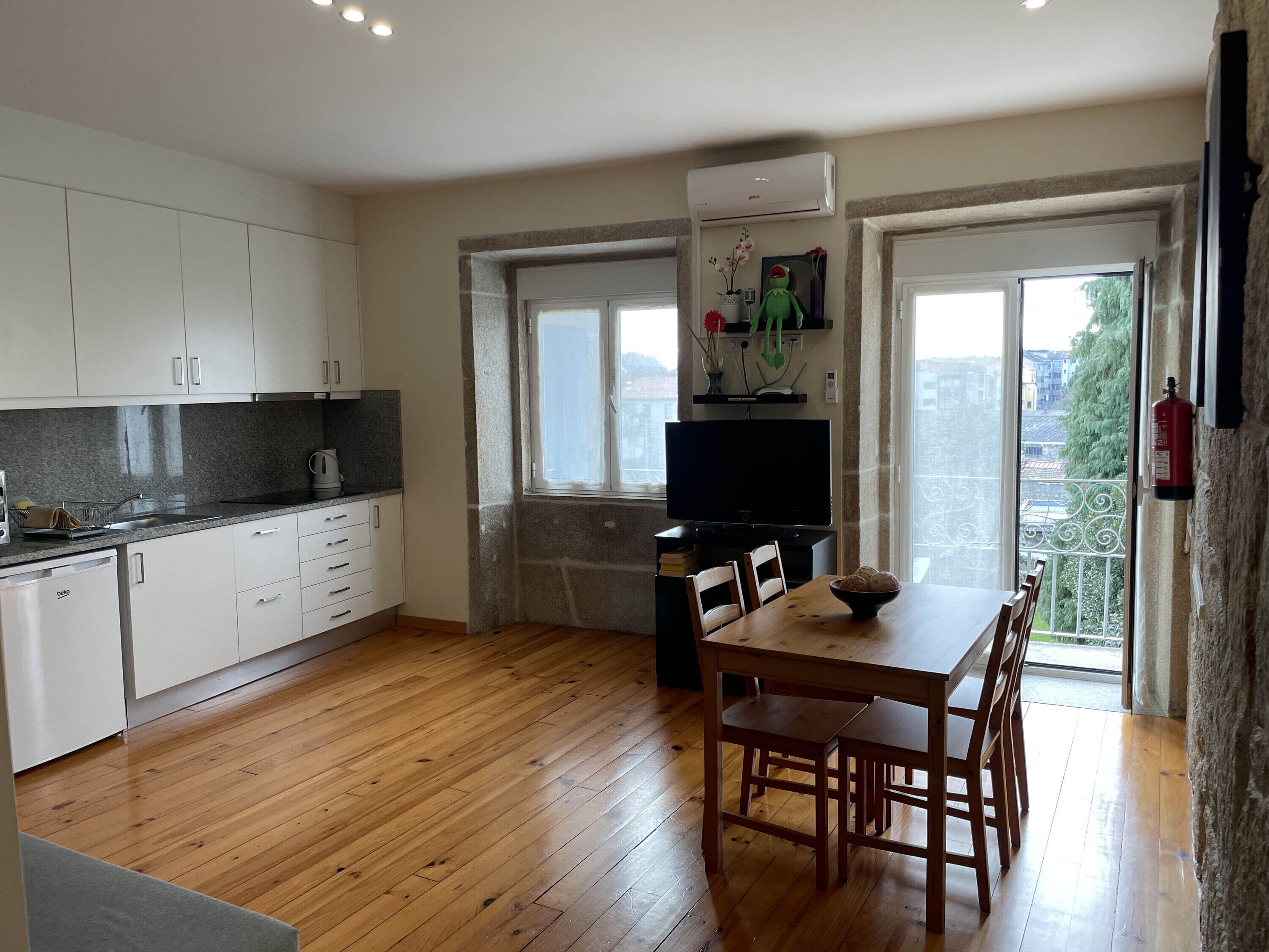 Een moderne keuken met witte kasten, een granieten aanrecht en een houten eettafel met stoelen.