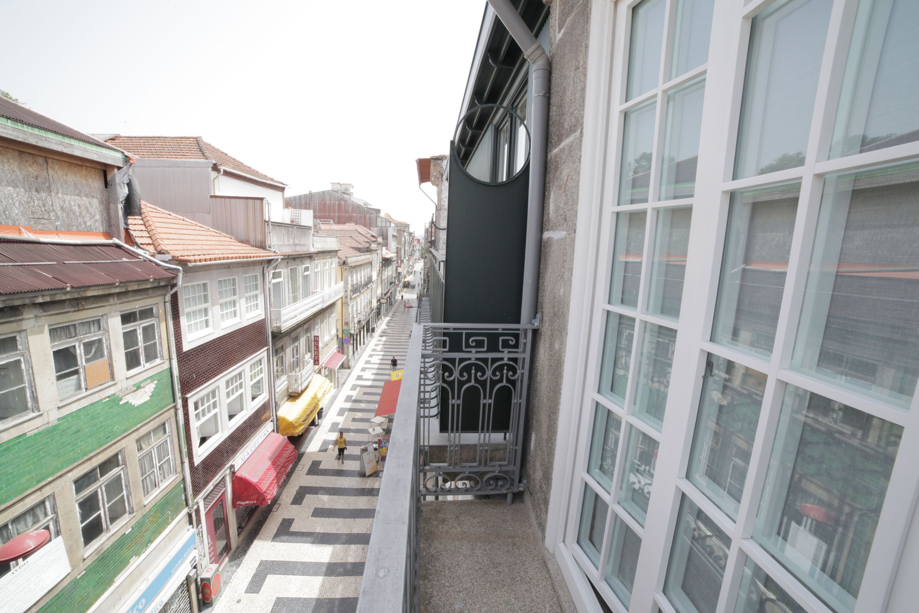 Une rue étroite en milieu urbain, bordée de bâtiments des deux côtés, avec un passage piéton et un autobus jaune.