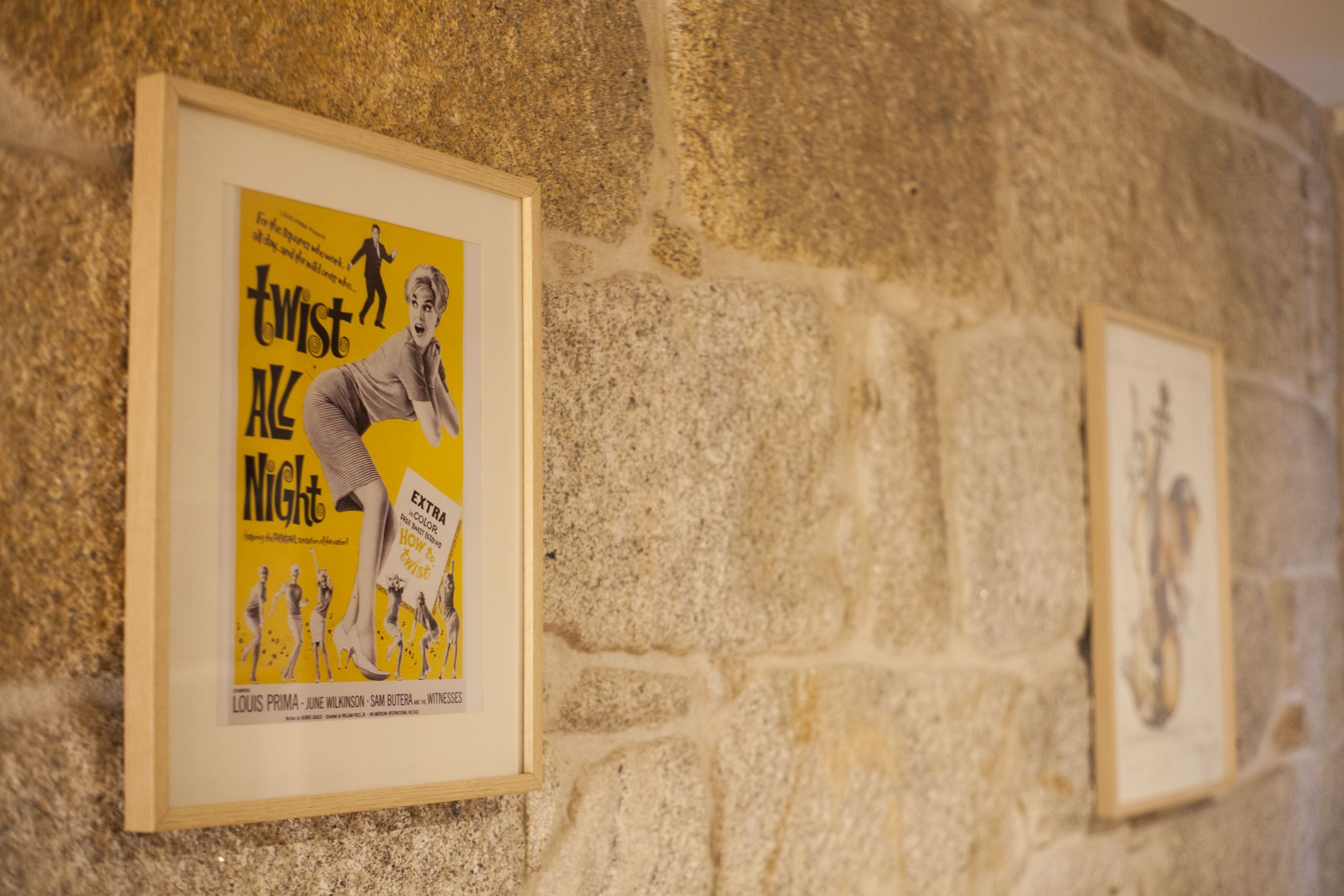 Une affiche de film ancienne, encadrée, accrochée à un mur de pierre.