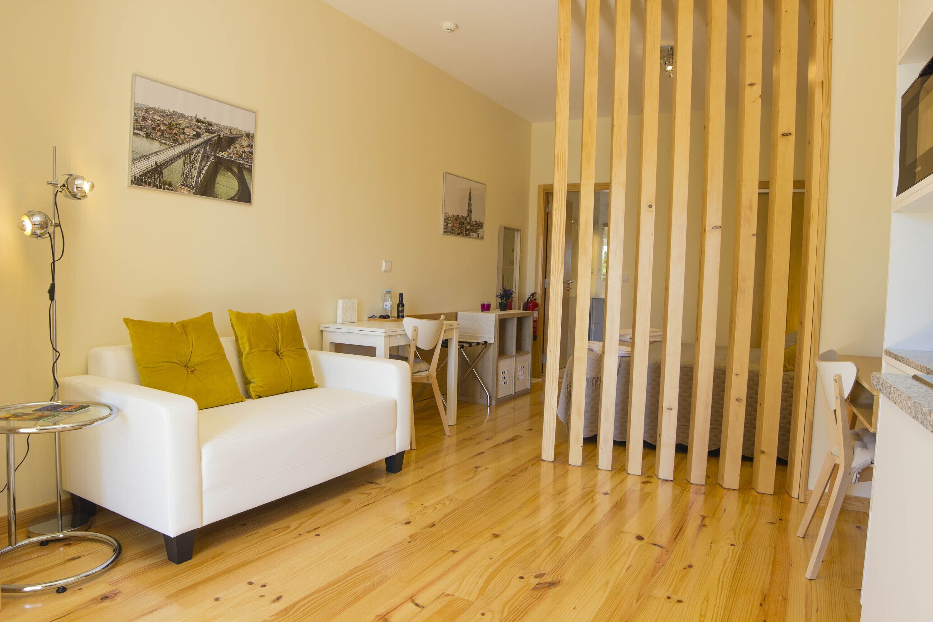 Een moderne woonkamer met een witte bank, houten vloer en een eethoek met een tafel en stoelen.