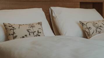 A bed with white bedding and two pillows with a floral pattern.