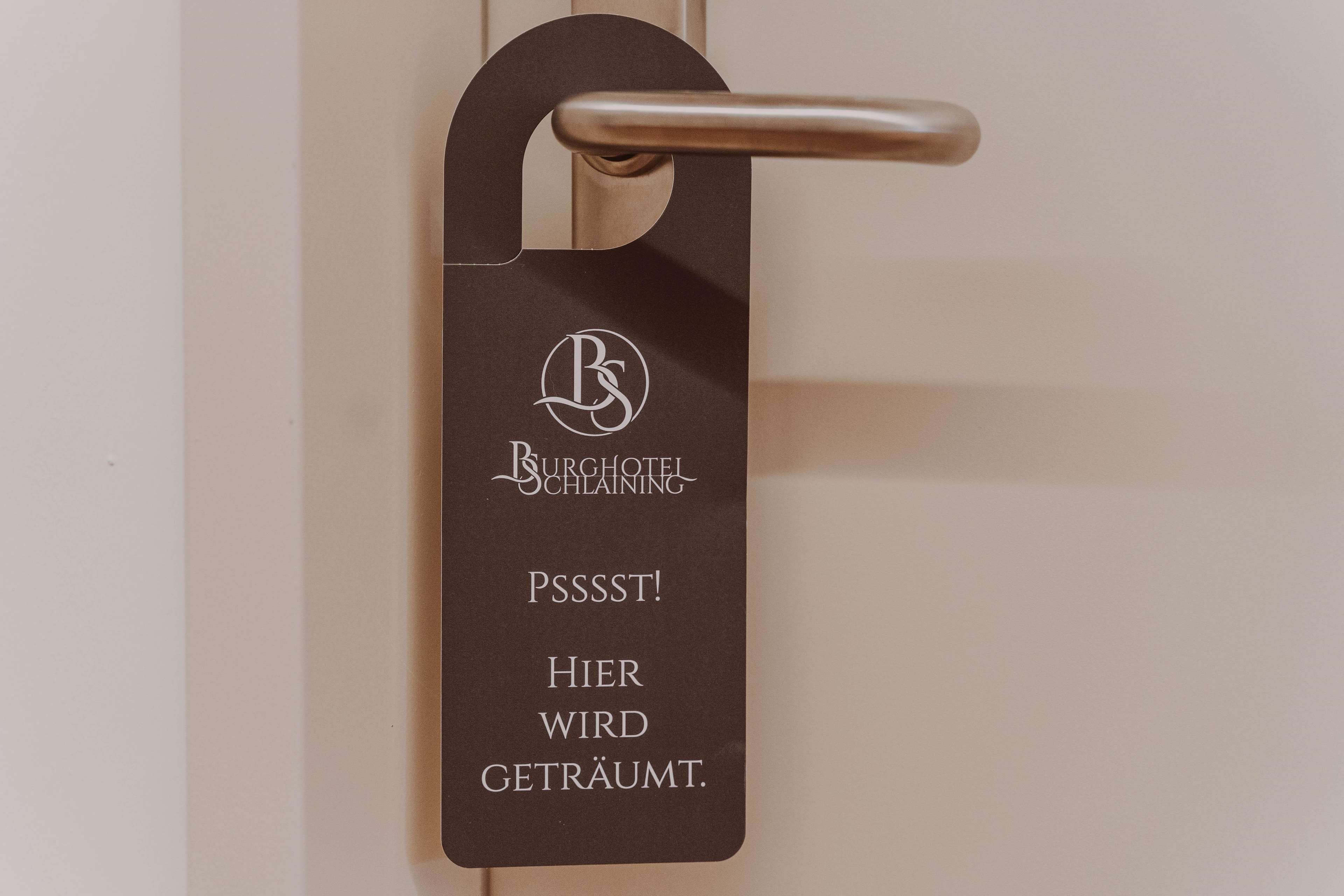 Un pomo de puerta con una etiqueta que dice "Burghotel Schläaning" y "¡Psst! Aquí se sueña."