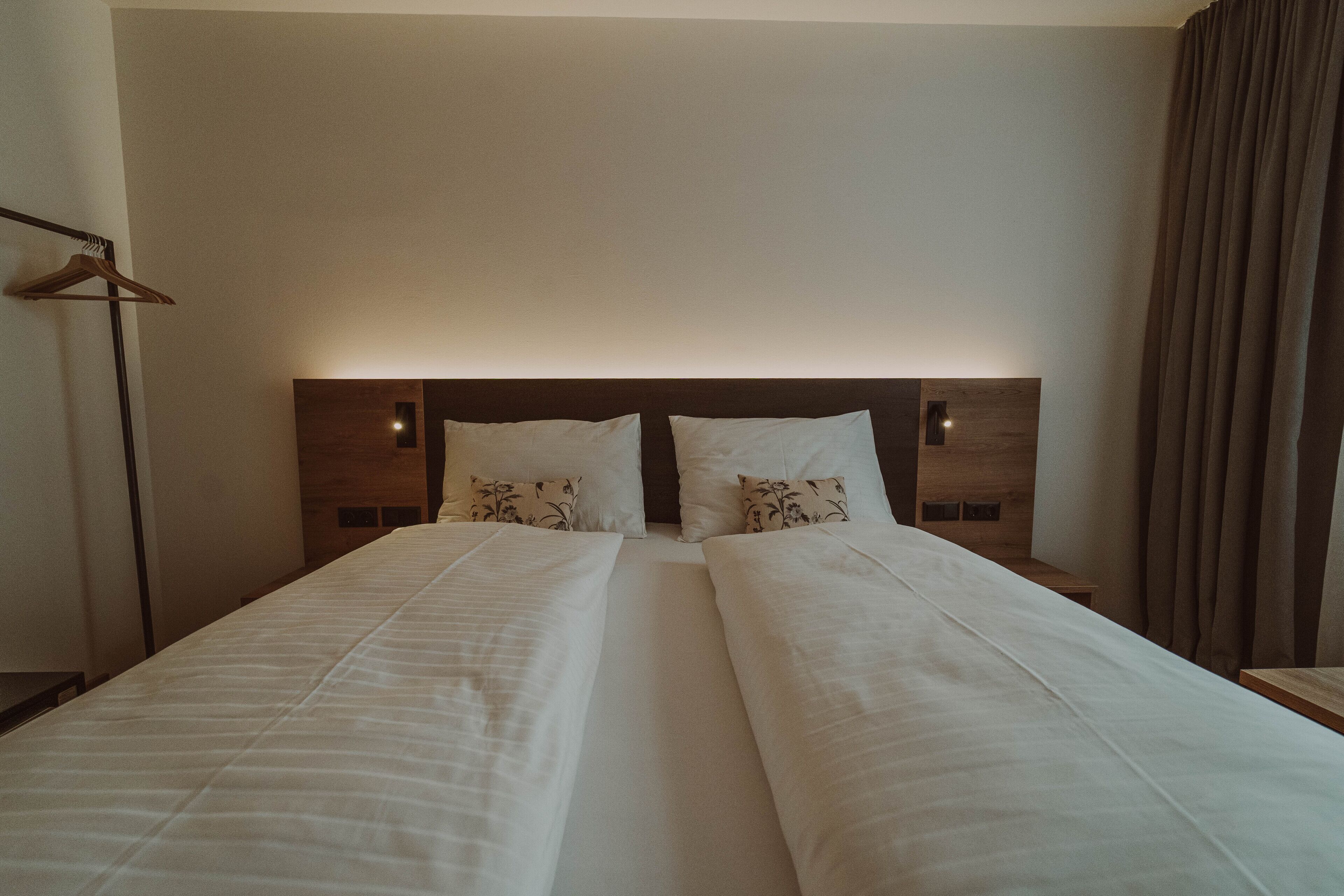 Ein Doppelbett mit Holz-Kopfteil und zwei Nachttischen.