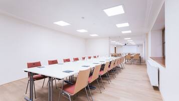 A conference room with a long table, red chairs, and a whiteboard.