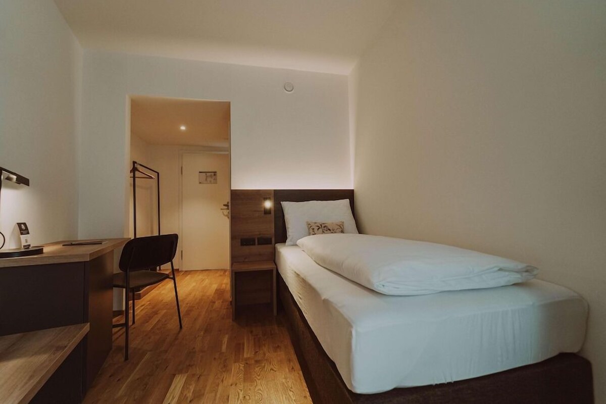 Hotellihuone, jossa on sänky, työpöytä ja tuoli.