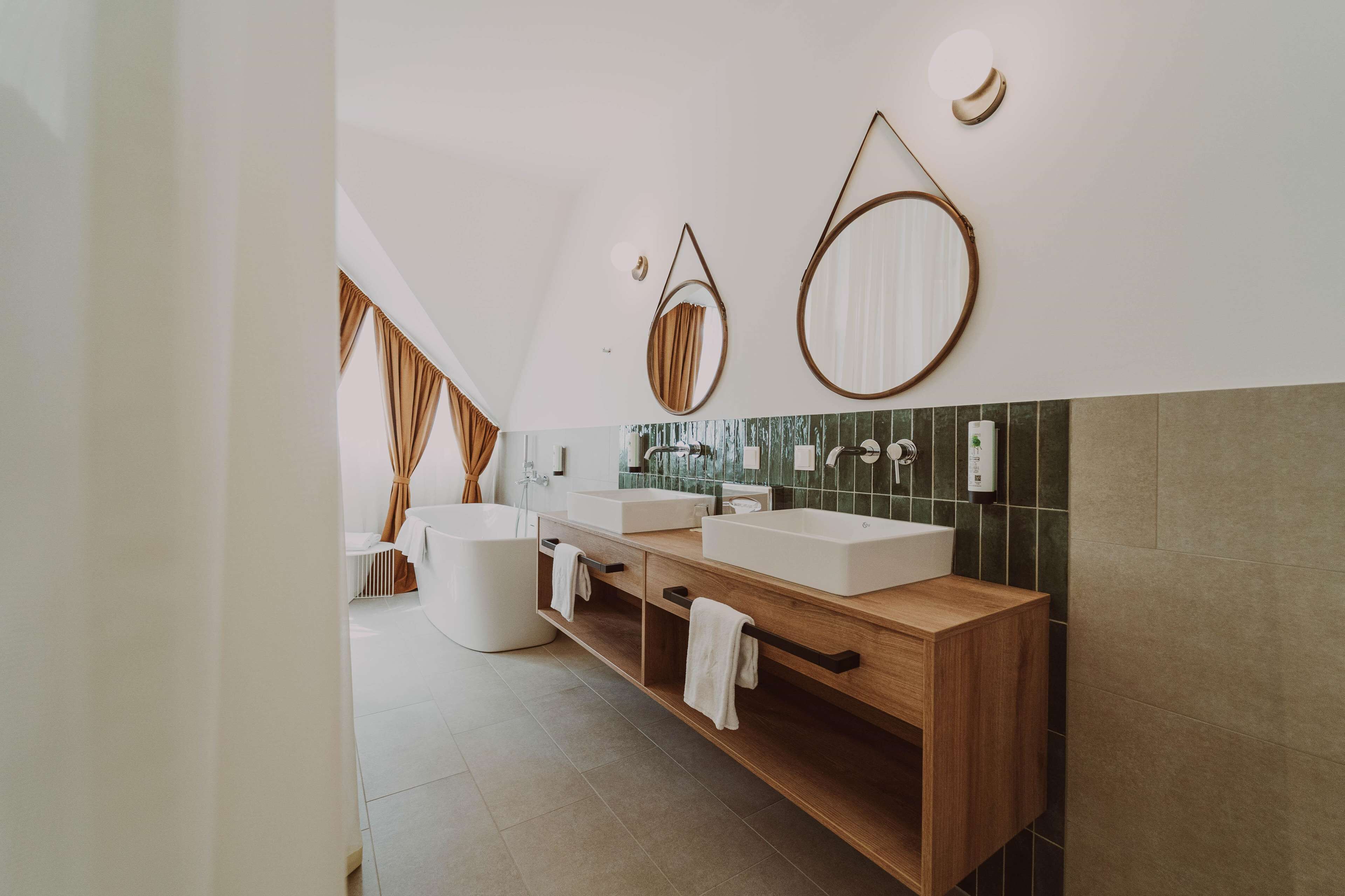 Un baño moderno con una bañera independiente, dos lavamanos y un mueble de tocador de madera.