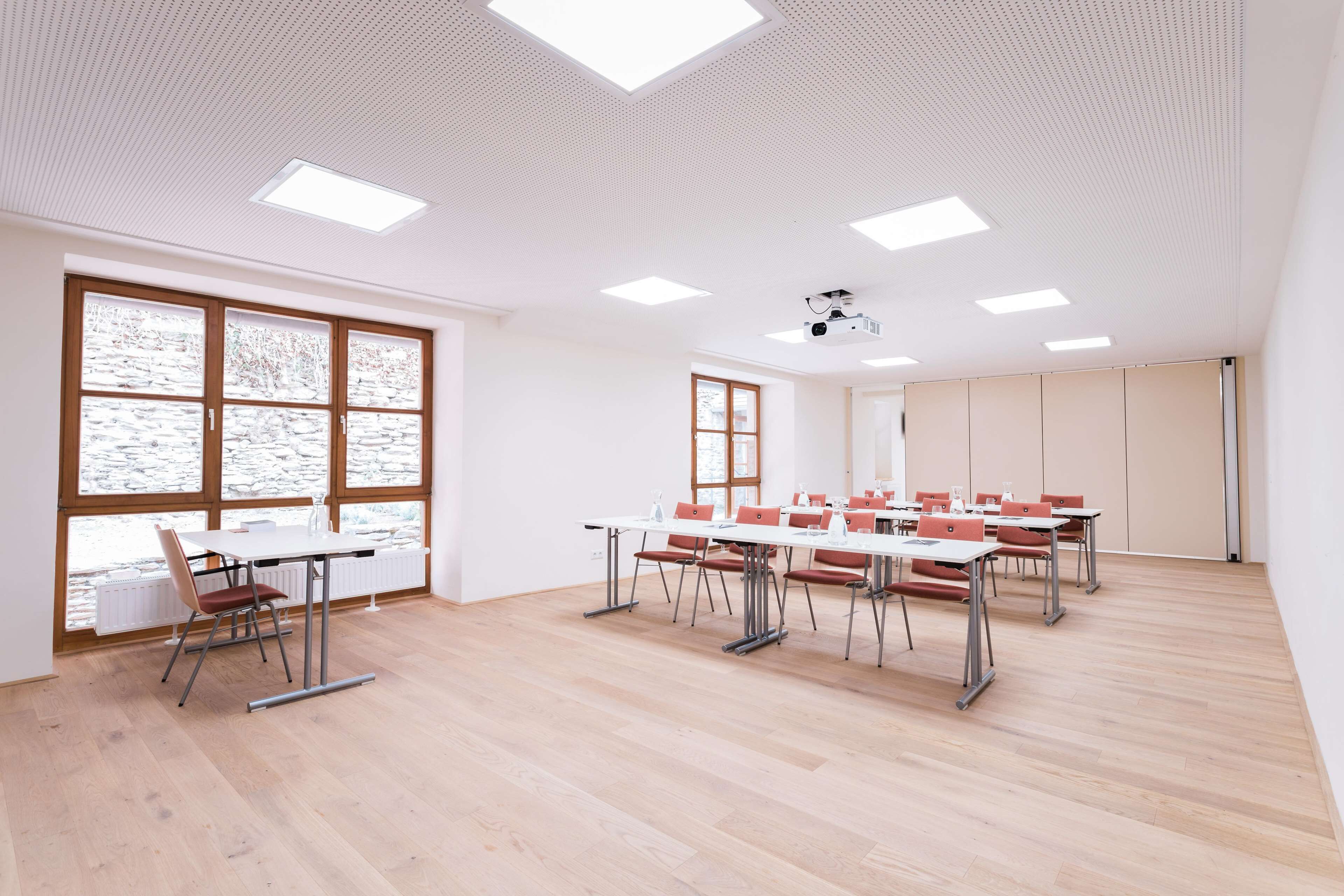 A conference room with a long table, multiple chairs, and a projector.