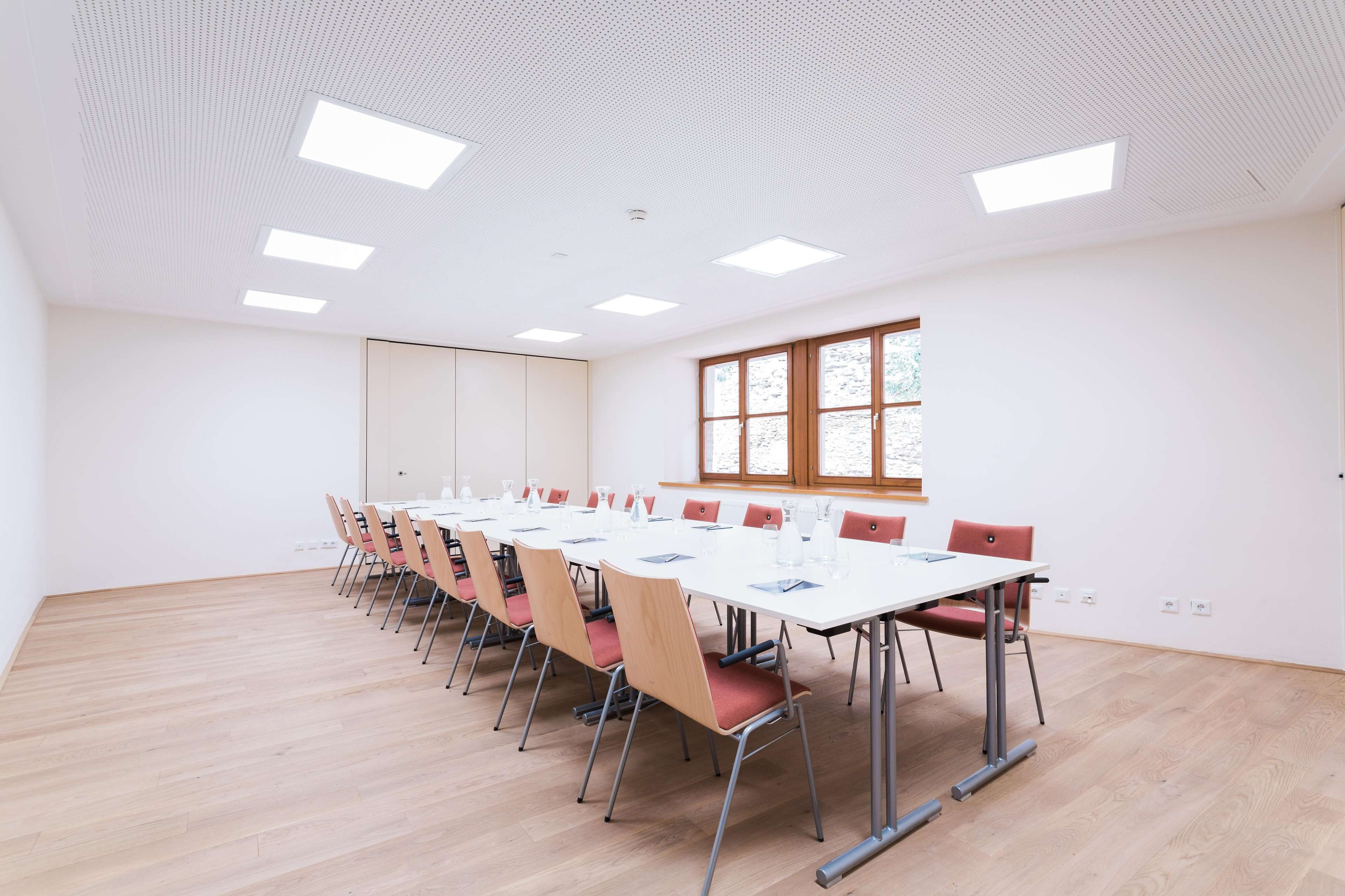 Una sala conferenze con un lungo tavolo, sedie e un'ampia finestra.