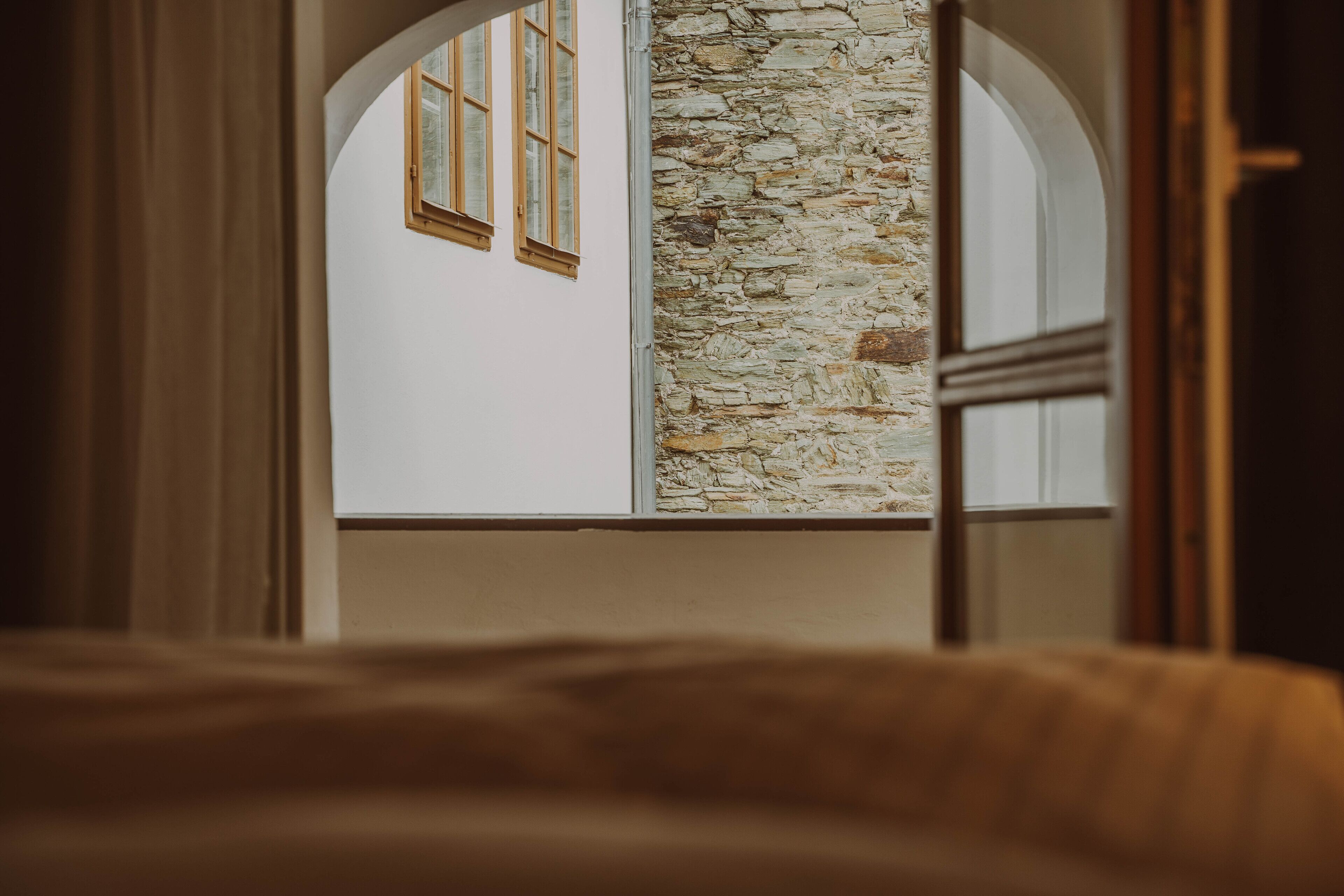 A room with a stone wall and arched windows.