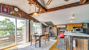 A spacious kitchen with a large island, wooden beams, and a view of trees. - Waterfront Glen Lake Cabin w/ Boat Dock & Deck (Queensbury)