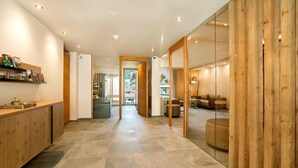 A modern hotel lobby with a reception desk, wooden accents, and a view of the outdoor area. - Alpin Apartments (Ramsau im Zillertal)