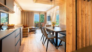 A modern kitchen with a dining area, wooden ceiling, and large windows offering a view of greenery. - Alpin Apartments (Ramsau im Zillertal)