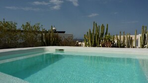 A clear blue pool with a white edge, surrounded by cacti and a white building with a dome structure in the background. - Villa Mare Bella Ciao Sea view private pool A / C 500m from the beach (Puerto del Carmen)
