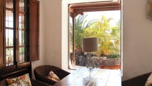 A room with wicker furniture, a wooden table, and a view of tropical plants outside. - Villa Mare Bella Ciao Sea view private pool A / C 500m from the beach (Puerto del Carmen)
