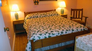 A bedroom with a wooden bed, two bedside lamps, a wooden chair, and a window with a view of trees. - Quiet neighborhood near beaches, bayou and historic downtown Ocean Springs. (Ocean Springs)