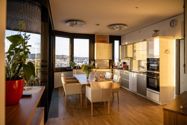 Une cuisine moderne avec un coin repas, de grandes fenêtres et une vue sur la ville.