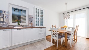 Una cocina moderna con armarios blancos, encimera de madera y zona de comedor con mesa y sillas de madera.