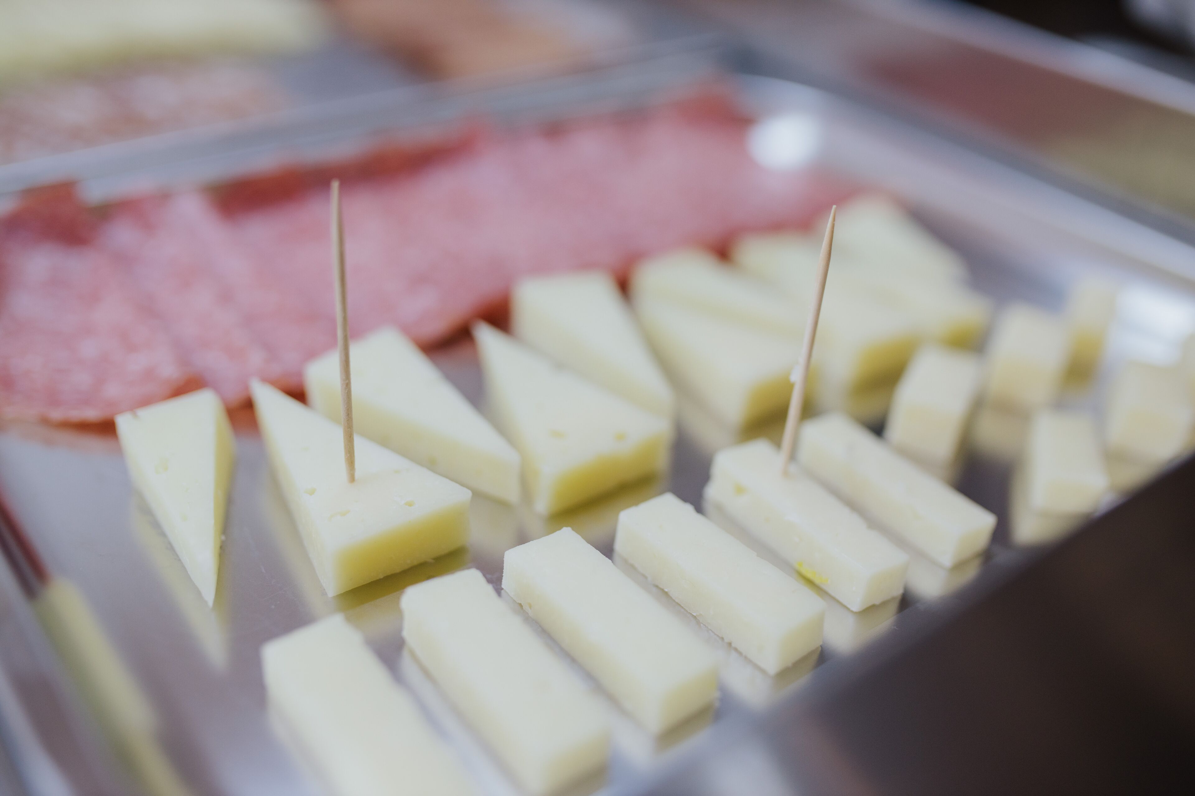 Un plateau contenant divers aliments, notamment des morceaux de fromage de forme rectangulaire et des tranches de viande.