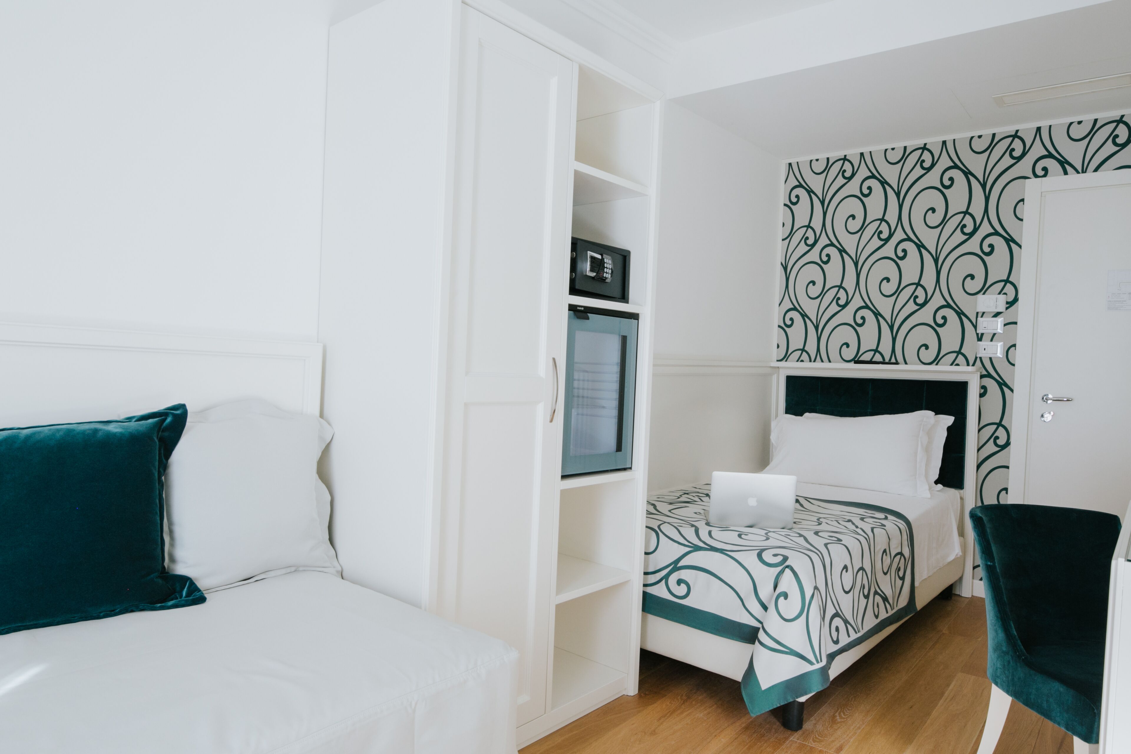 A hotel room with a bed, a desk, a chair, a wardrobe, and a microwave.
