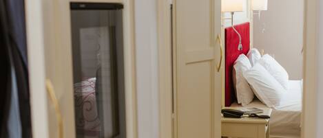 A hotel room with a bed, a bedside table, a mirror, and a wardrobe.