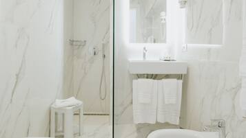 Un baño moderno con ducha envuelta en vidrio, una bañera independiente y un tocador con espejo.