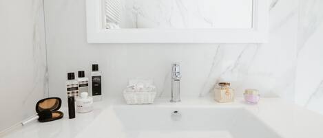 A bathroom with a white marble sink, a mirror, and various toiletries.