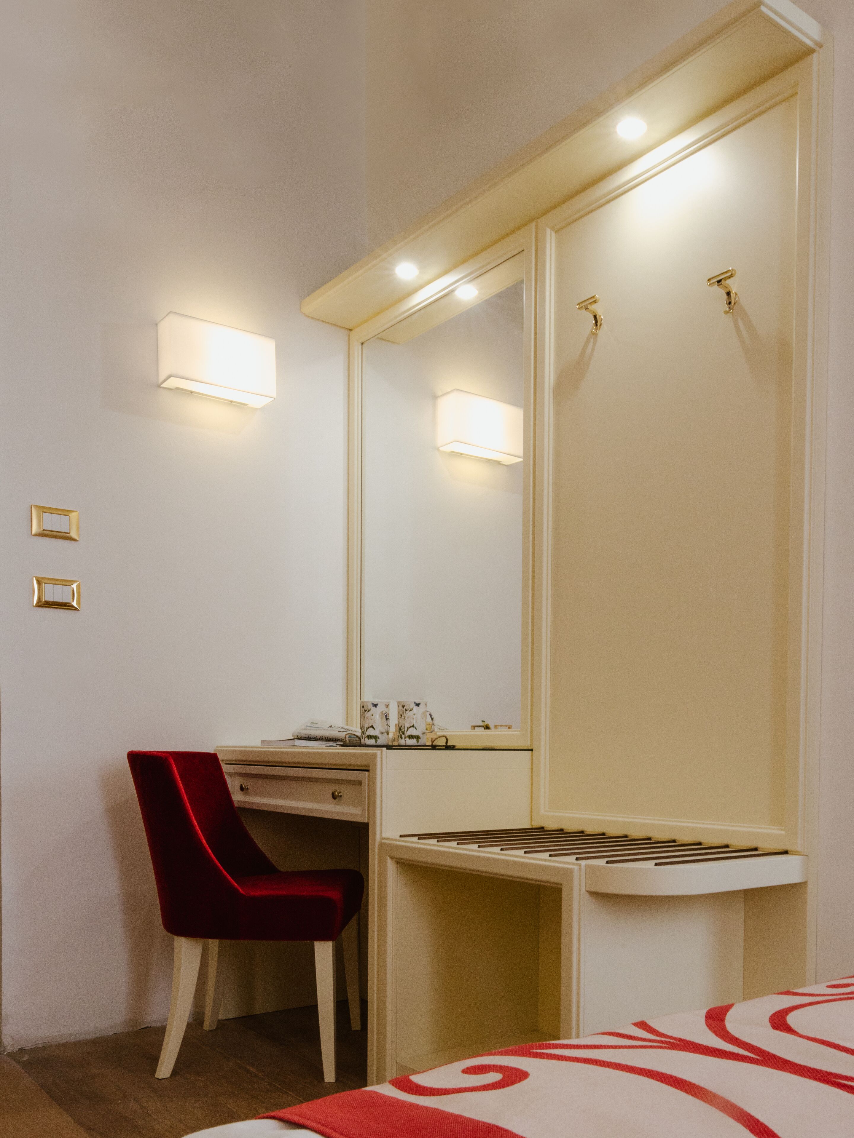 A hotel room with a desk, chair, and a large mirror with integrated lighting.