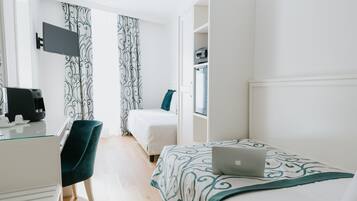 Una habitación de hotel con escritorio, silla, cama, laptop, televisor y armario.
