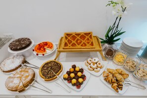 Une grande variété de desserts et de pâtisseries sont présentés sur une table de buffet, notamment des gâteaux, des tartes et des beignets.