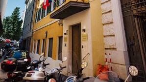A yellow building with multiple windows and balconies, parked motorcycles, and a clear blue sky. - Hotel Città di Parenzo (Trieste)