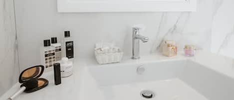 A bathroom with a marble sink, a mirror, and various toiletries.