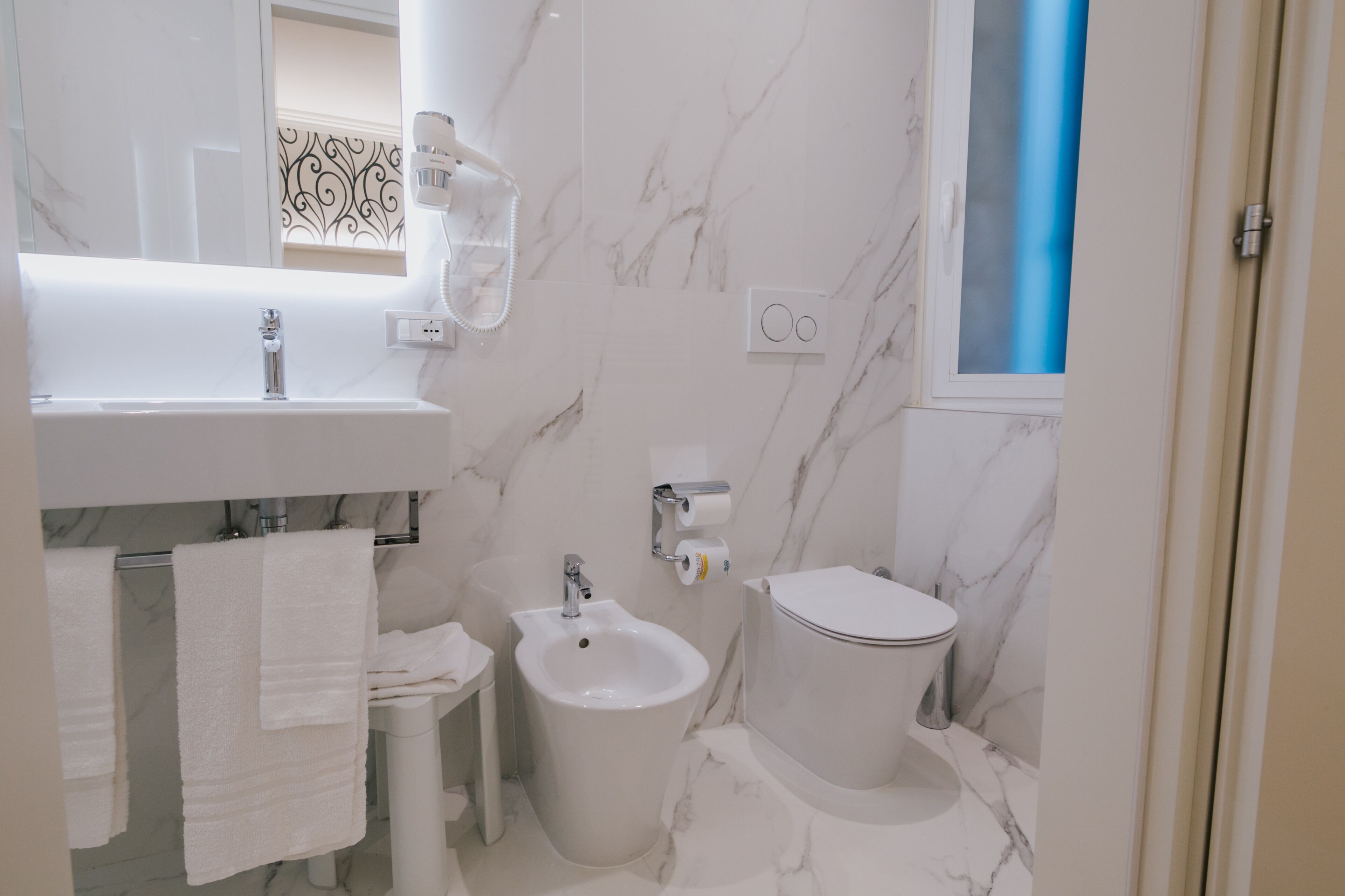 Un baño con lavabo, bidé, inodoro y espejo.