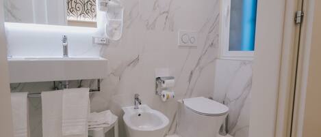Un baño con lavabo, bidé, inodoro y espejo.