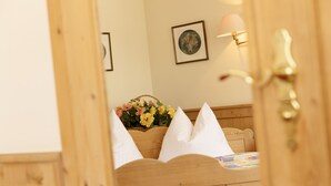 A wooden bed with white pillows and a floral arrangement on the headboard. - Hotel Hoyacker Hof (Garching)