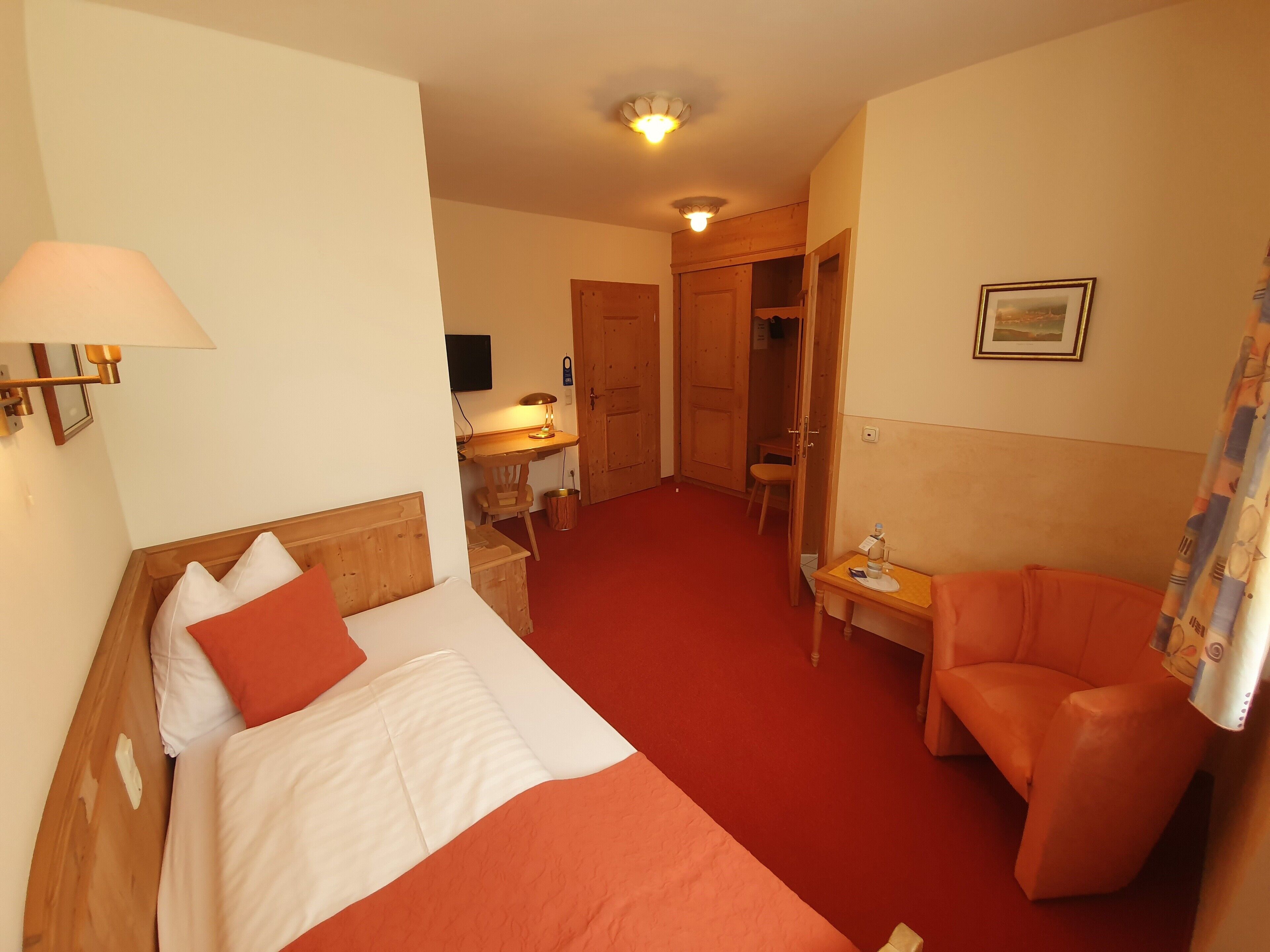 Een hotelkamer met een bed, een stoel, een bureau en een badkamer.