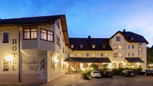 A hotel with a traditional European architectural style, featuring a large entrance with a covered walkway and multiple cars parked in front. - Hotel Hoyacker Hof (Garching)