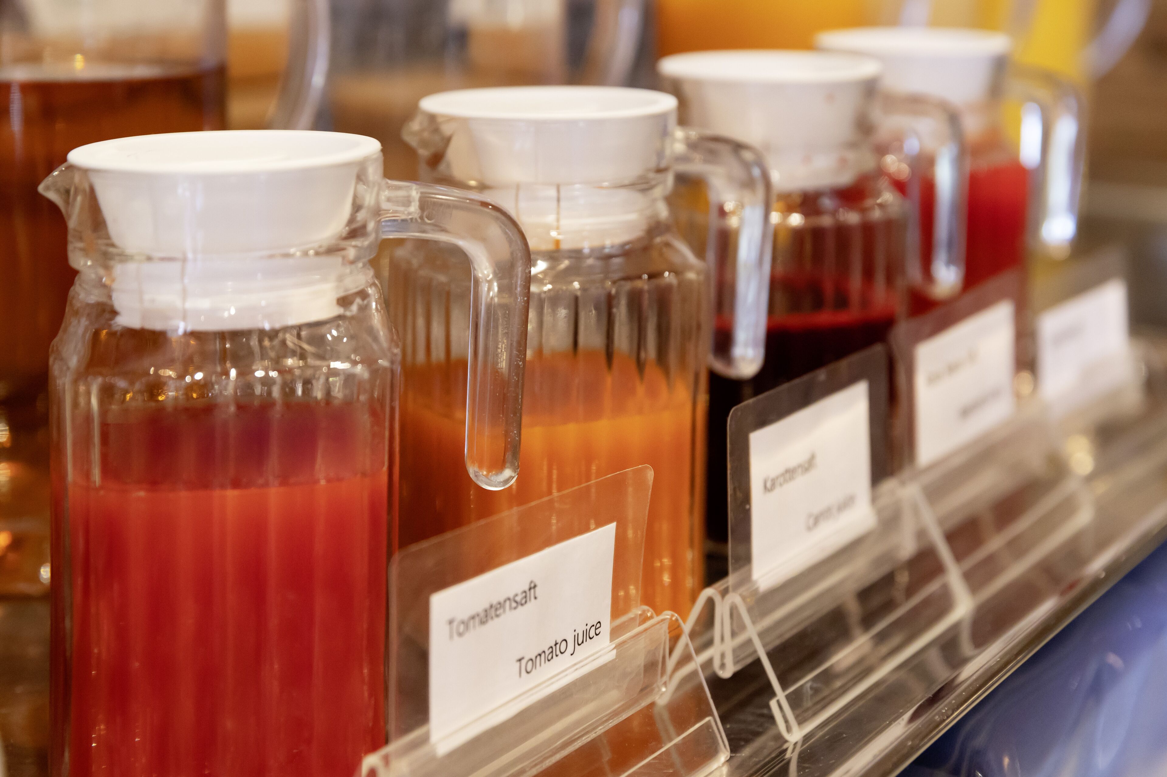 Une sélection de boissons proposées dans des contenants en verre, avec étiquettes, notamment du jus de tomate.