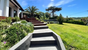 Escadaria de concreto que leva a uma casa com jardim.