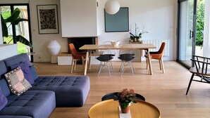 Uma sala de estar moderna com sofá, mesa de centro e área de jantar com cadeiras.