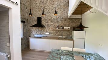 A modern kitchen with a stone backsplash, pendant lights, a microwave, and a glass-top table.