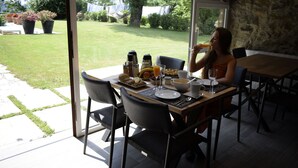An outdoor dining area with a table set for two, featuring a variety of breakfast items and a glass of orange juice. - Casa Rural Martiamuno Landetxea (Zumarraga)