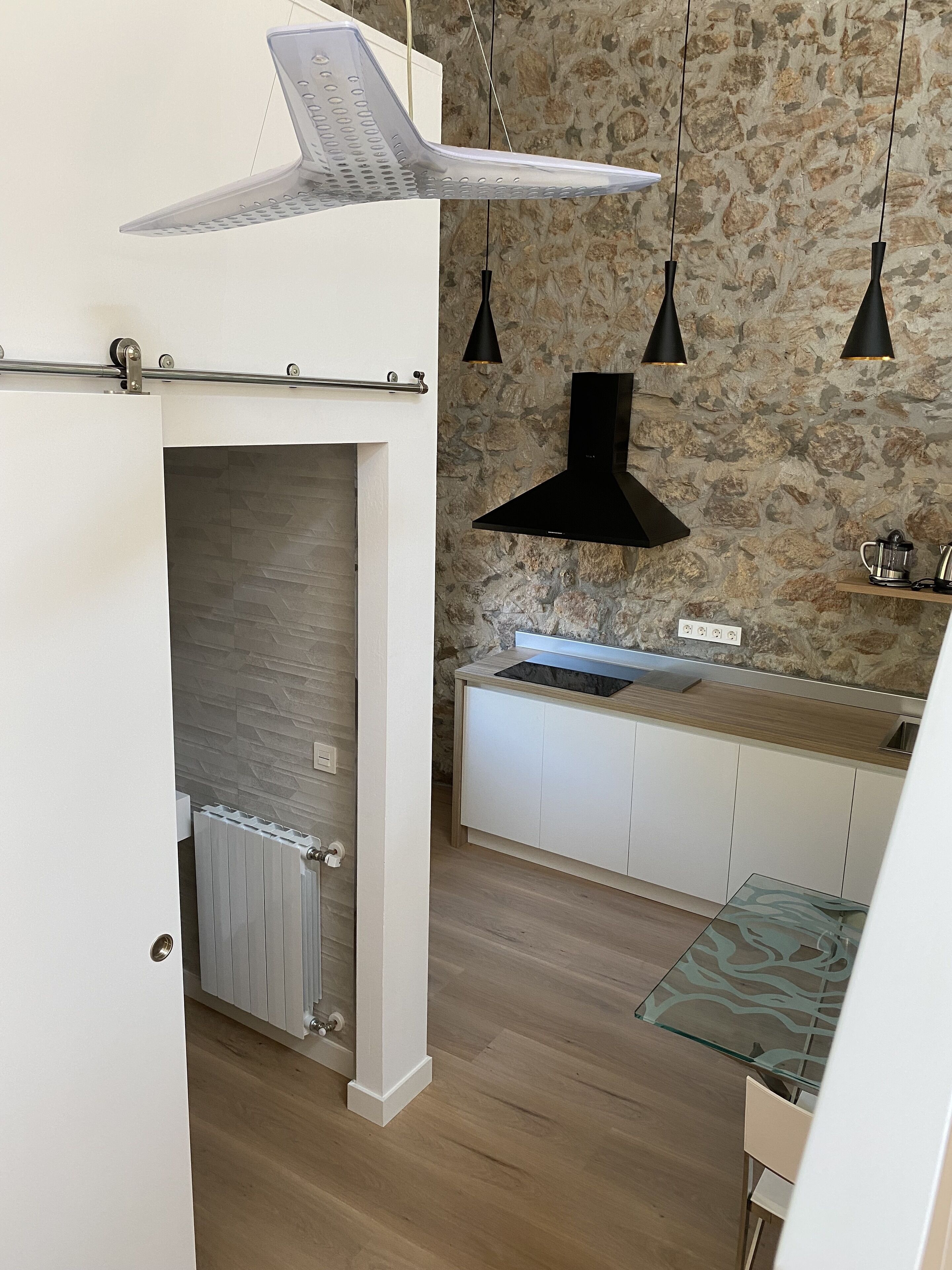 Eine moderne Küche mit Steinrückwand, weißer Arbeitsplatte und einer schwarzen Dunstabzugshaube.