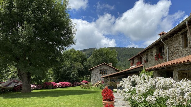 A stone building with a garden, a hammock, and a stone pathway. - Casa Rural Martiamuno Landetxea (Zumarraga)