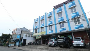 Un edificio de varios pisos con un restaurante Chicken Day en la planta baja.