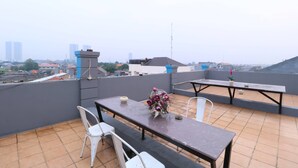 Una terraza en la azotea con una mesa, sillas, un arreglo floral y vistas panorámicas de la ciudad.
