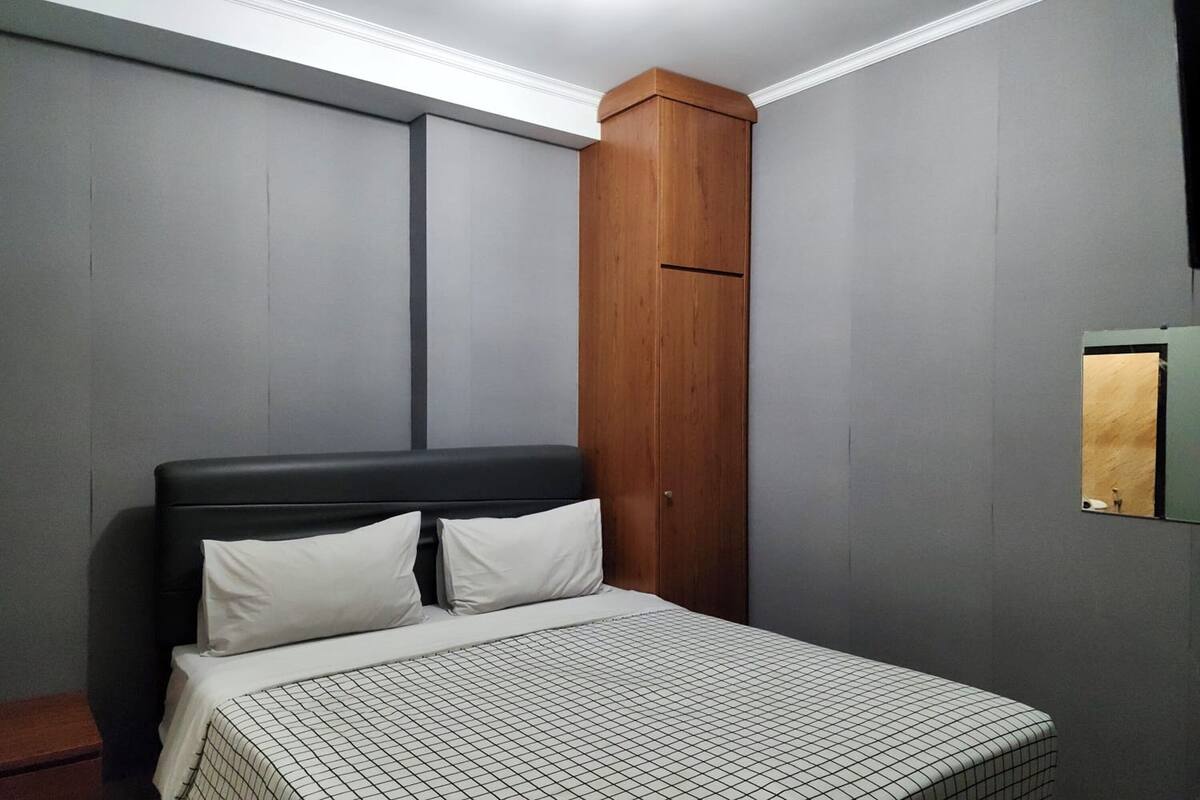 Quarto com cama, guarda-roupa de madeira e espelho pequeno.