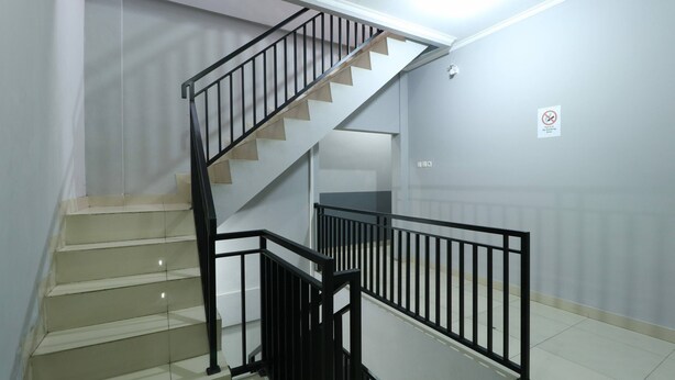 Una escalera con barandas negras y escalones color beige.